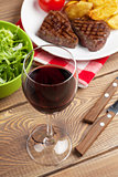 Glass of red wine and steak with salad
