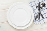 Empty plate and silverware over wooden table
