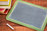 blank slate blackboard with chalk and books