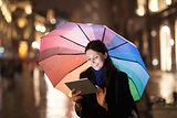 Woman using pad under umbrella in the evening city