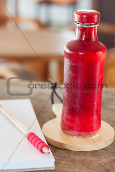 Red syrup in the bottle on wooden plate