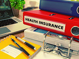 Red Office Folder with Inscription Health Insurance.