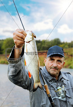 chub in the hand of fisherman against the sky and the river