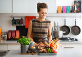 smiling woman in kitchen sorting autumn vegetables