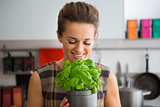 Smiling woman holding and smelling pot of fresh basil