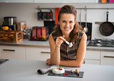 Smiling woman leaning on counter having Camembert cheese