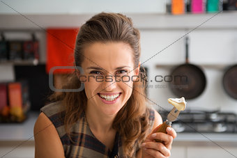 Closeup of smiling woman holding Camembert slice on cheese fork
