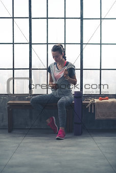 Woman removing sweatshirt while sitting in loft gym