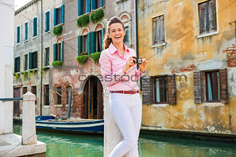 Laughing woman tourist in Venice holding camera near canal