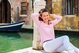 Laughing woman sitting against pillar on pier in Venice