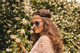 profile portrait of happy hippie young woman among flowers