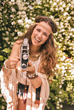 closeup on bohemian young woman among flowers using retro camera