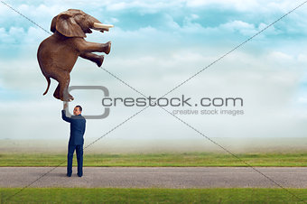 businessman holding an elephant with one finger 