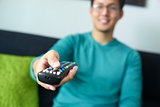 Asian Man Watching TV Changes Channel With Remote