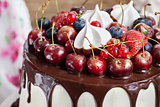 Cake decorated with chocolate, meringues and fresh berries