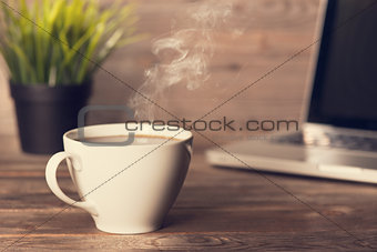 Hot coffee on wooden office desk 