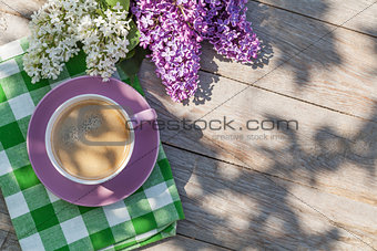 Coffee cup and colorful lilac flowers on garden table