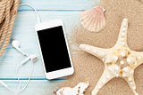 Smartphone on wood and sea sand with starfish and shells