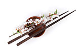 Chopsticks and sakura branch over soy sauce bowl