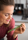 Smiling woman holding sprig of fresh rosemary in her hand