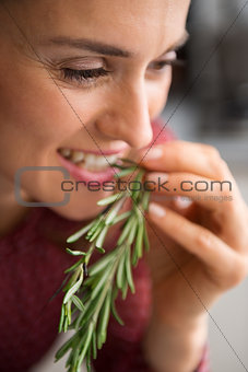 Closeup of smiling woman tasting fresh rosemary
