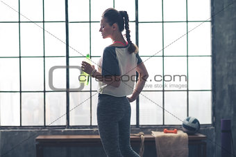 Profile view of fit woman holding water bottle in loft gym