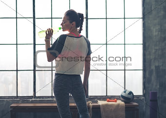 Fit woman in workout gear in profile drinking from water bottle