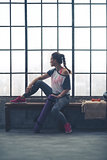 Fit woman sitting on loft gym bench looking out window