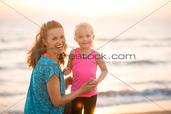 Portrait of young mother and daughter in workout gear on beach