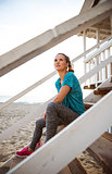 Woman in fitness gear sitting on steps at beach house