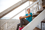 Woman in fitness gear relaxing on beach house steps