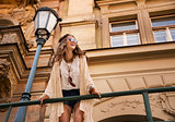 smiling boho chic with sunglasses near old town streetlight