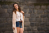 portrait of smiling boho young woman near stone wall