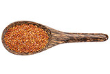 red quinoa grain on wooden spoon