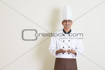 Handsome Indian male chef in uniform holding a plate