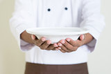 Indian male chef in uniform presenting an empty plate