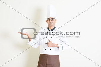 Indian male chef in uniform presenting a coffee cup and thumb up