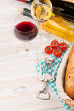 White and red wine, cheese and bread on white wooden table backg