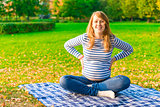 Pregnant woman resting on a plaid autumn park