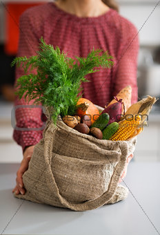 Closeup of burlap sac filled with fall vegetables with woman
