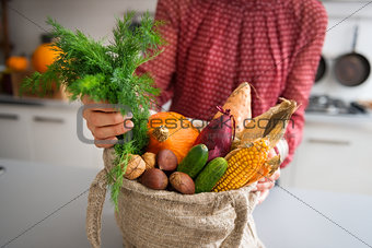 Closeup of fall vegetables and nuts in burlap bag held by woman