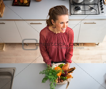 From above, smiling woman in kitchen with fall vegetables