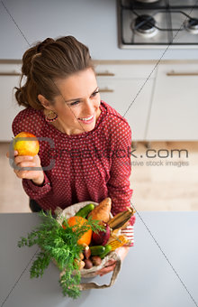 Woman smiling and holding apple and fall vegetables in kitchen