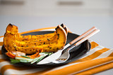 Closeup of pumpkin with herbs and cutlery on dark plate