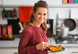 Closeup of woman smiling in kitchen while holding plate of food