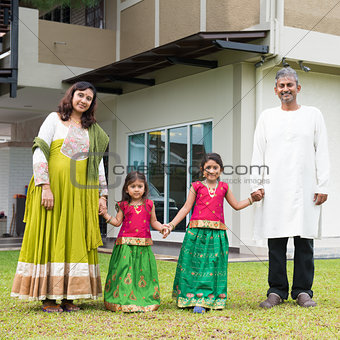 Indian family holding hands outside new home
