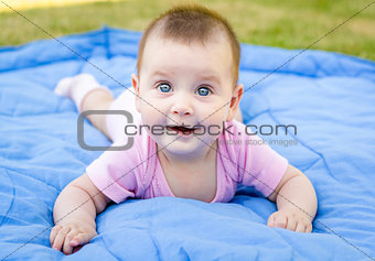 Cute little baby girl is smiling and playing on grass
