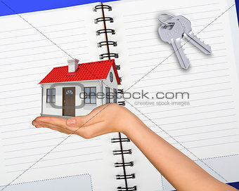 Humans hand holding house with keys
