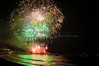 Fireworks display over sea with reflections