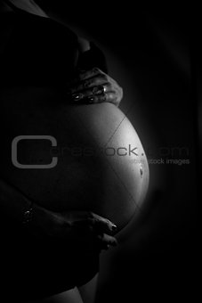 Black and white image of a woman\'s pregnant belly
